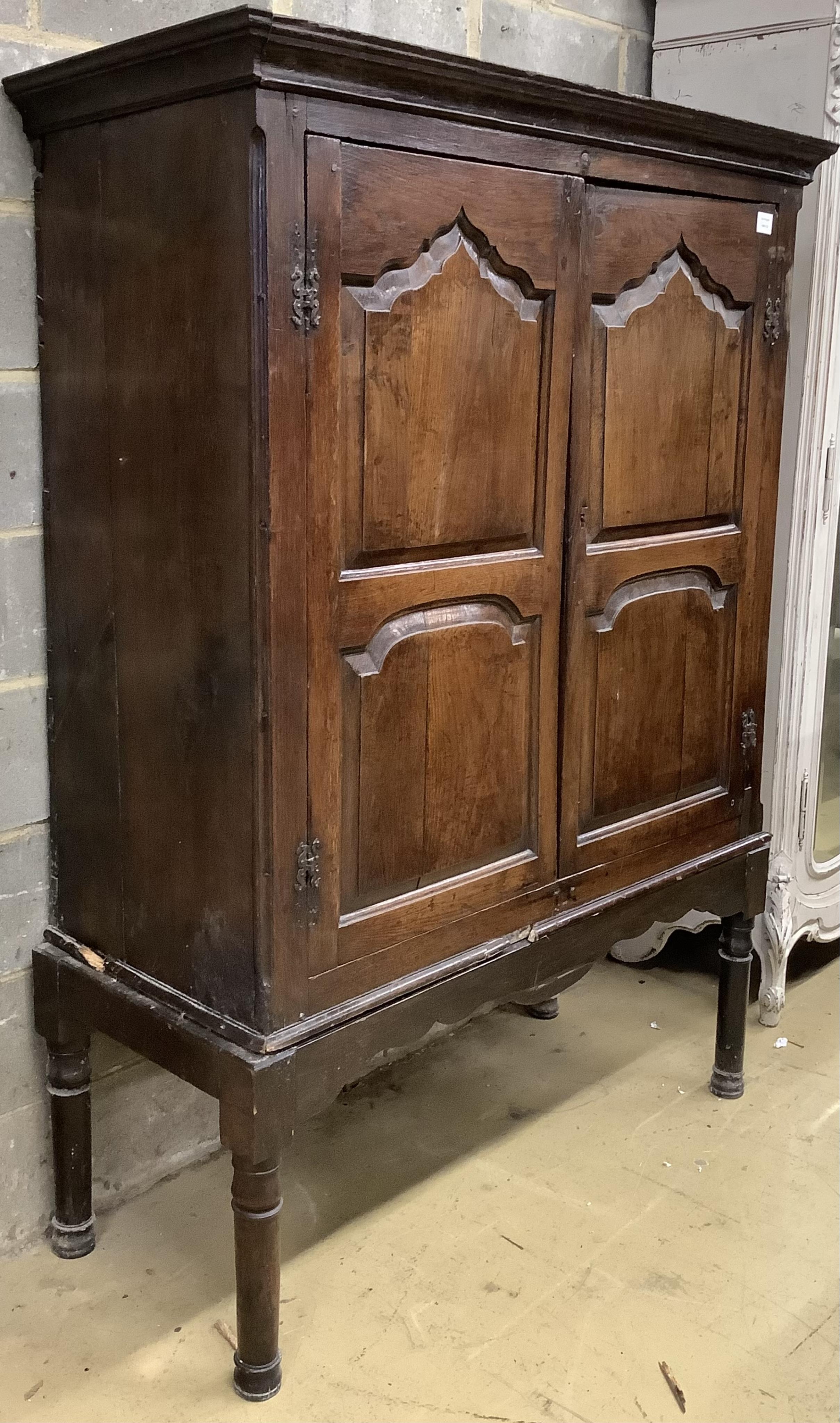 A mid 18th century carved oak cupboard, on associated stand, a.f., width 130cm, depth 55cm, height 178cm. Condition - poor